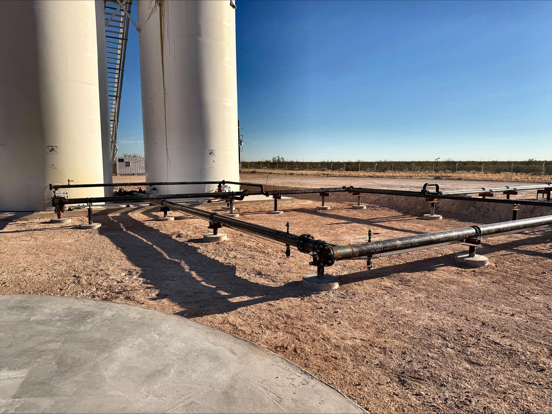 Pad piping and header on concrete supports at a central tank battery built by Encore