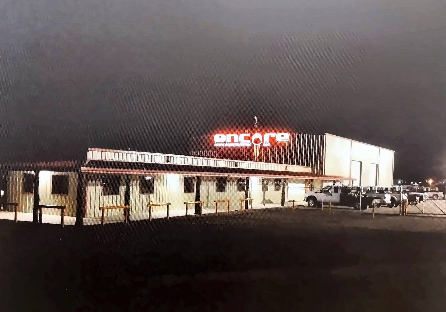 Encore Pipe & Construction yard and lit sign on Interstate 20 in Midland at night