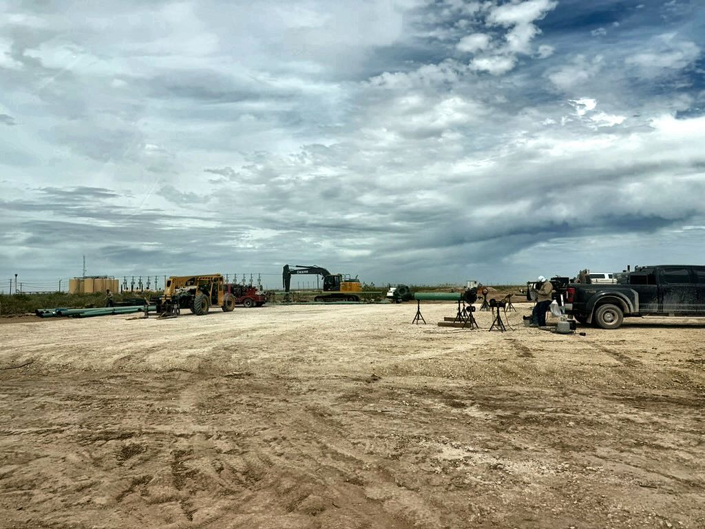 Pipeline laydown yard with excavator, telehandler and strung pipe